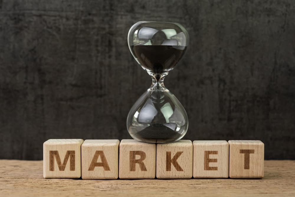 Time countdown for stock market, fluctuation on market, hourglass or sandglass on wooden cube block with alphabet building the word Market on wood table, dark black background.