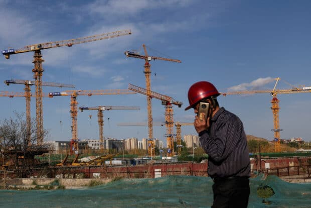 A worker speaking on his phone walks past a construction site in Beijing, China April 14, 2022. Picture taken April 14, 2022.